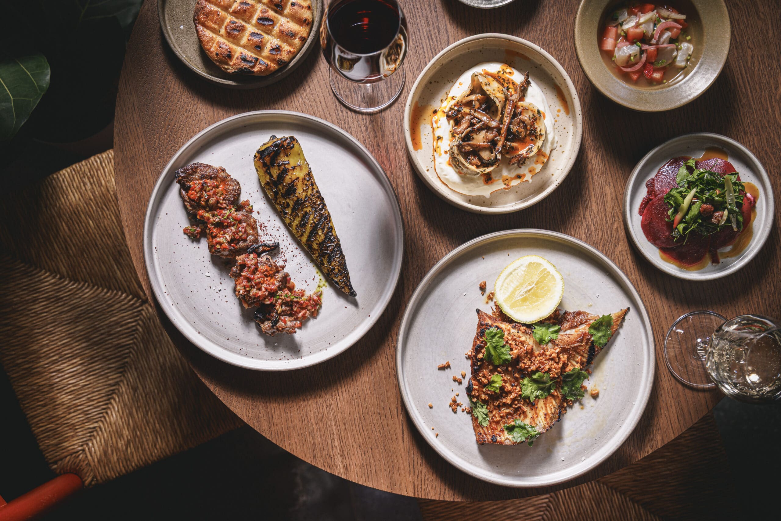 A vibrant table spread at Ara Restaurant in Aldgate East, City of London, featuring lamb neck, charred pepper, mushrooms dumpling with wild mushrooms, ceviche, beetroot salad, and wine.