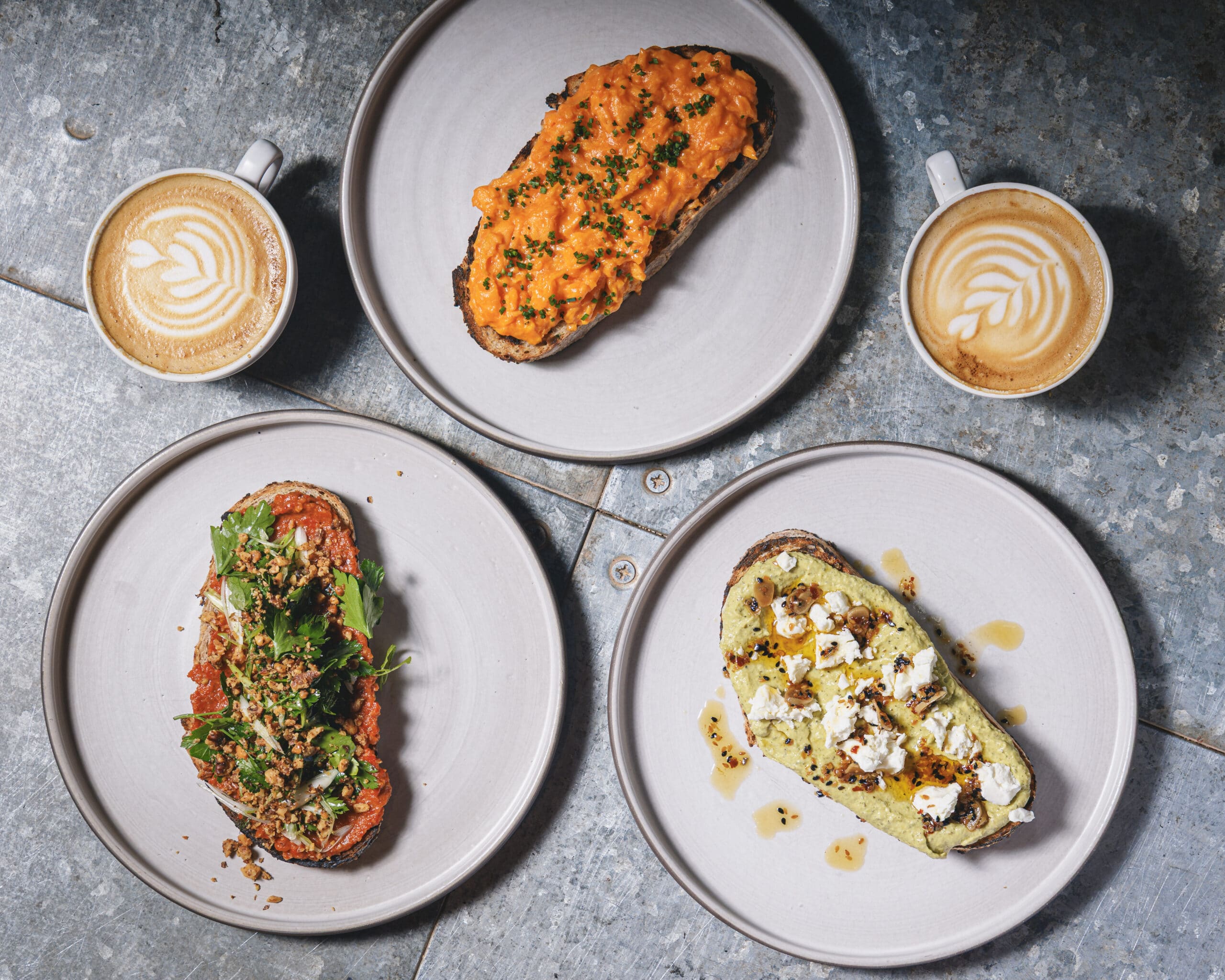 Sourdough toasts with vibrant toppings, Muhammara, scrambled eggs, courgette spread with feta and with latte art at Ara Restaurant near Spitalfields.