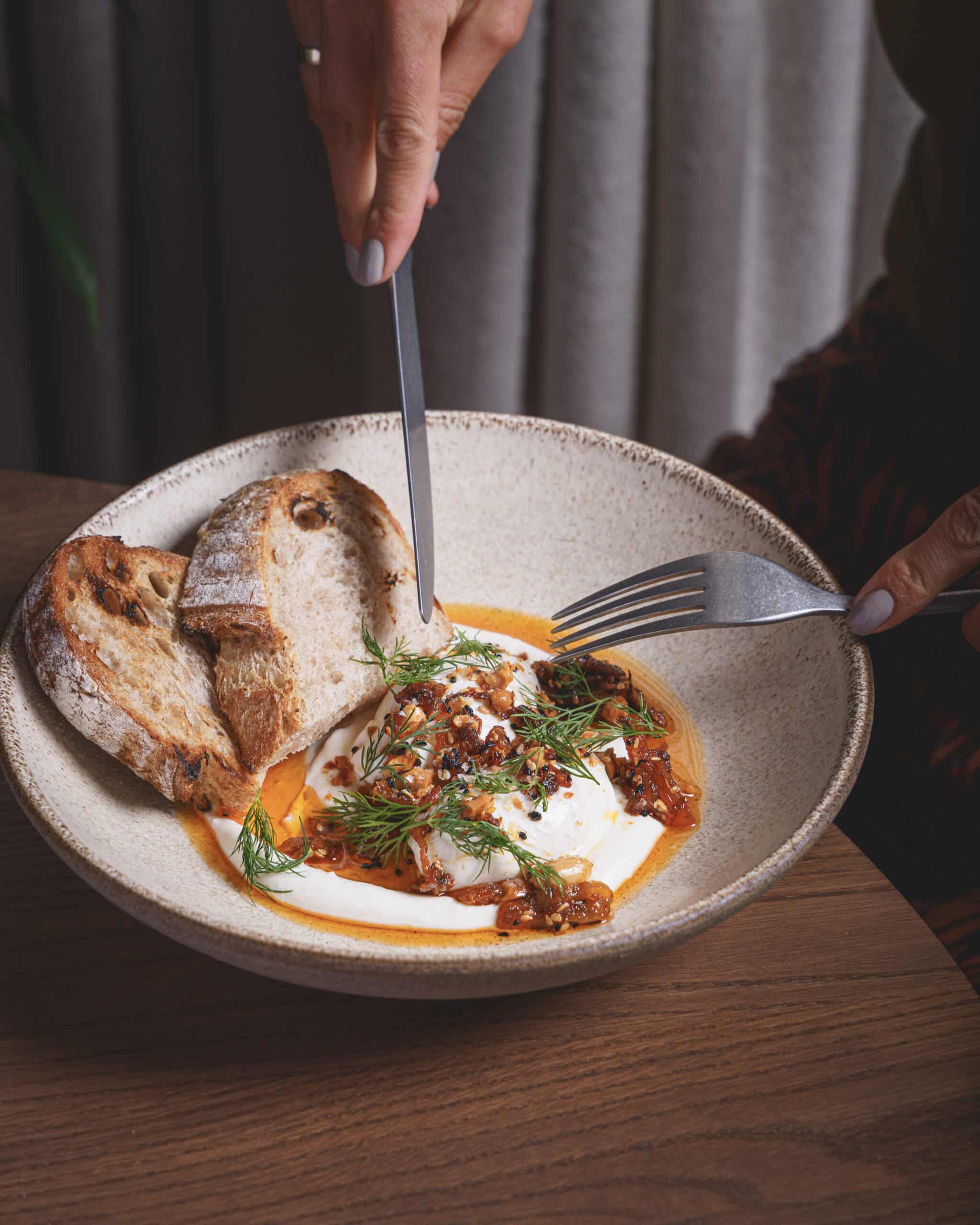 Turkish eggs with crispy chilli peanuts and garlic yogurt, served with sourdough at Ara Restaurant in Aldgate East, near Spitalfields and Shoreditch.