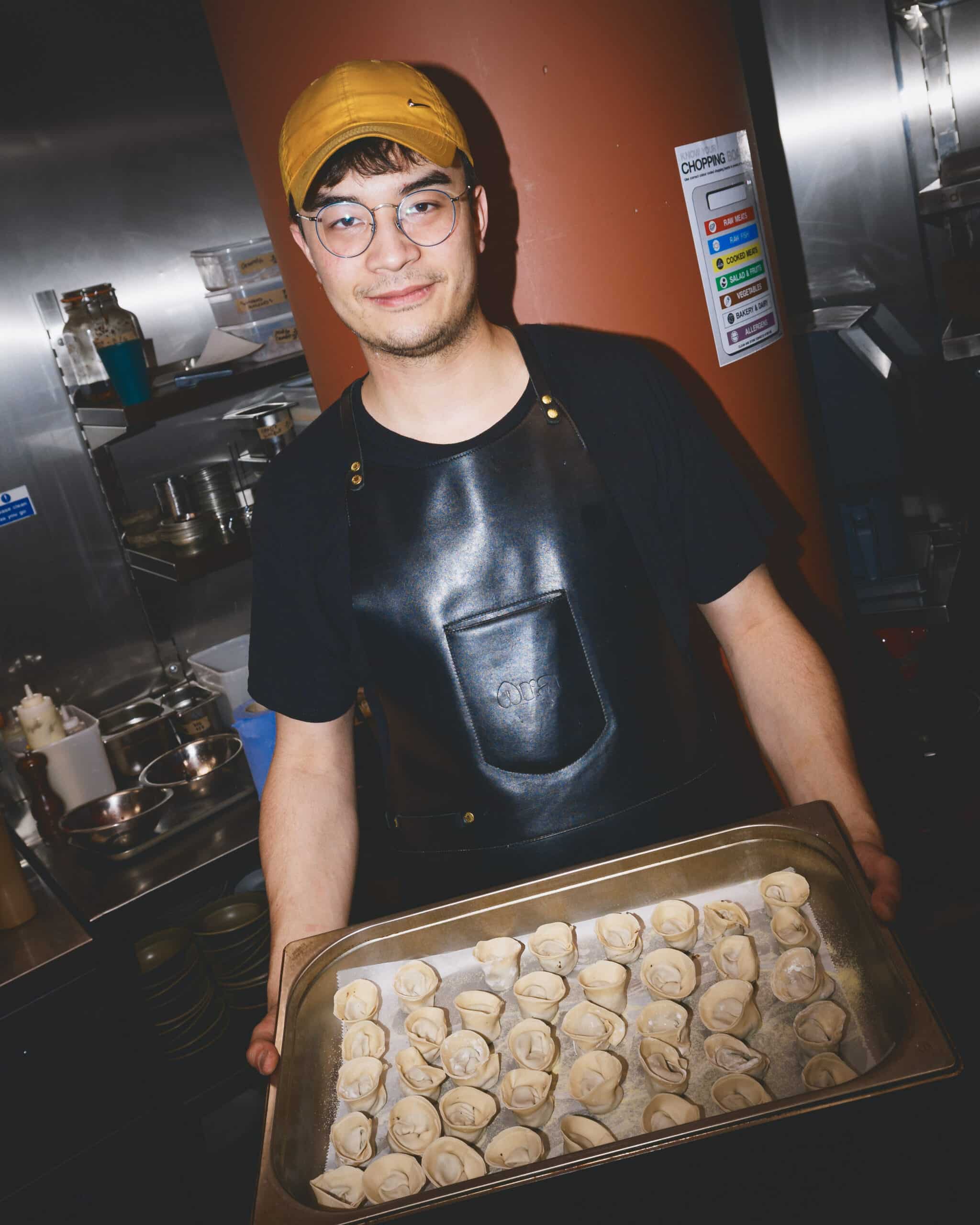 Ara Restaurant chef holding a tray of freshly handmade dumplings in the kitchen, located near Spitalfields and the City of London.