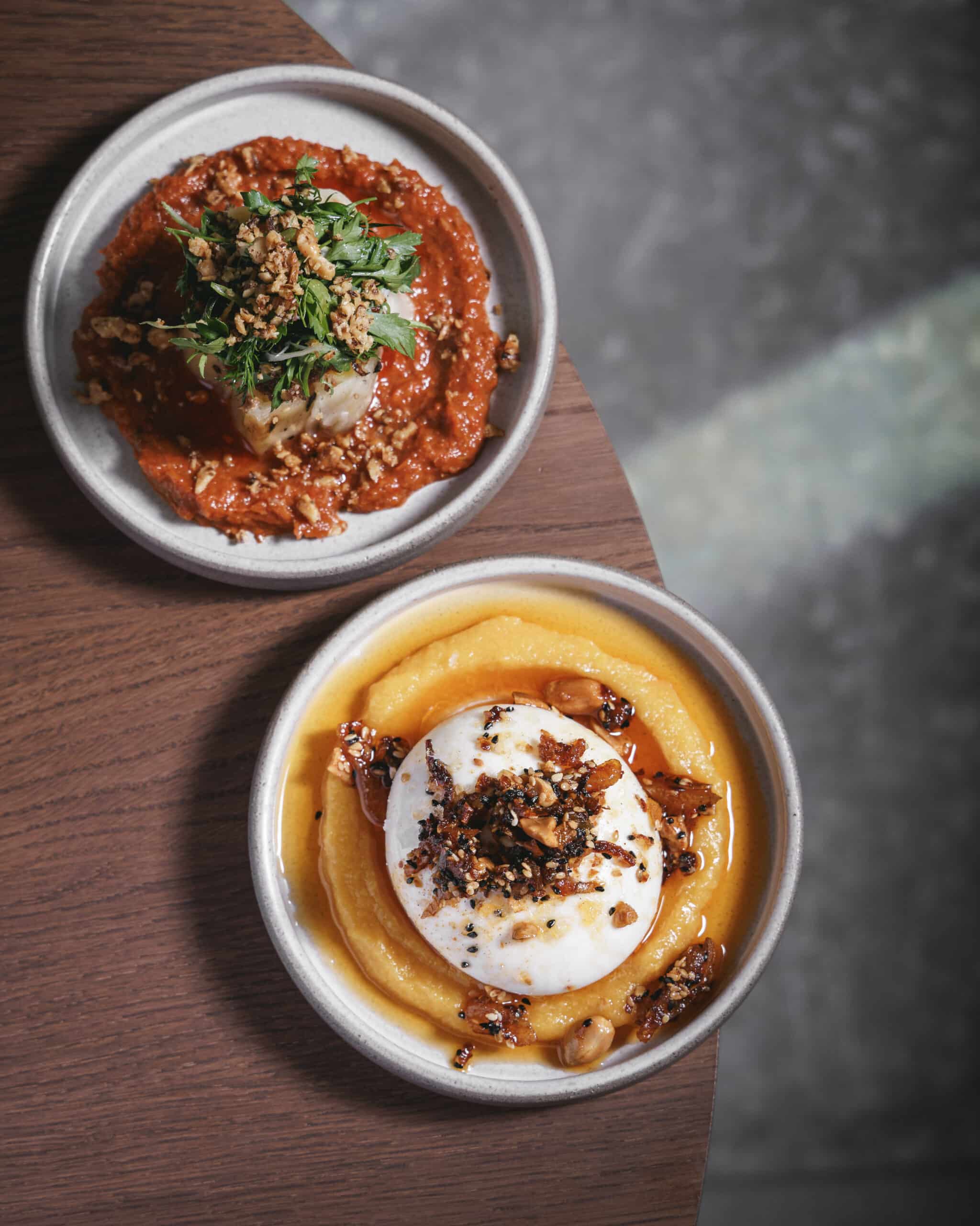 Confit leeks with muhammara and herbs alongside burrata with creamy apricot purée and crispy chilli peanuts, served at Ara Restaurant in Aldgate East.