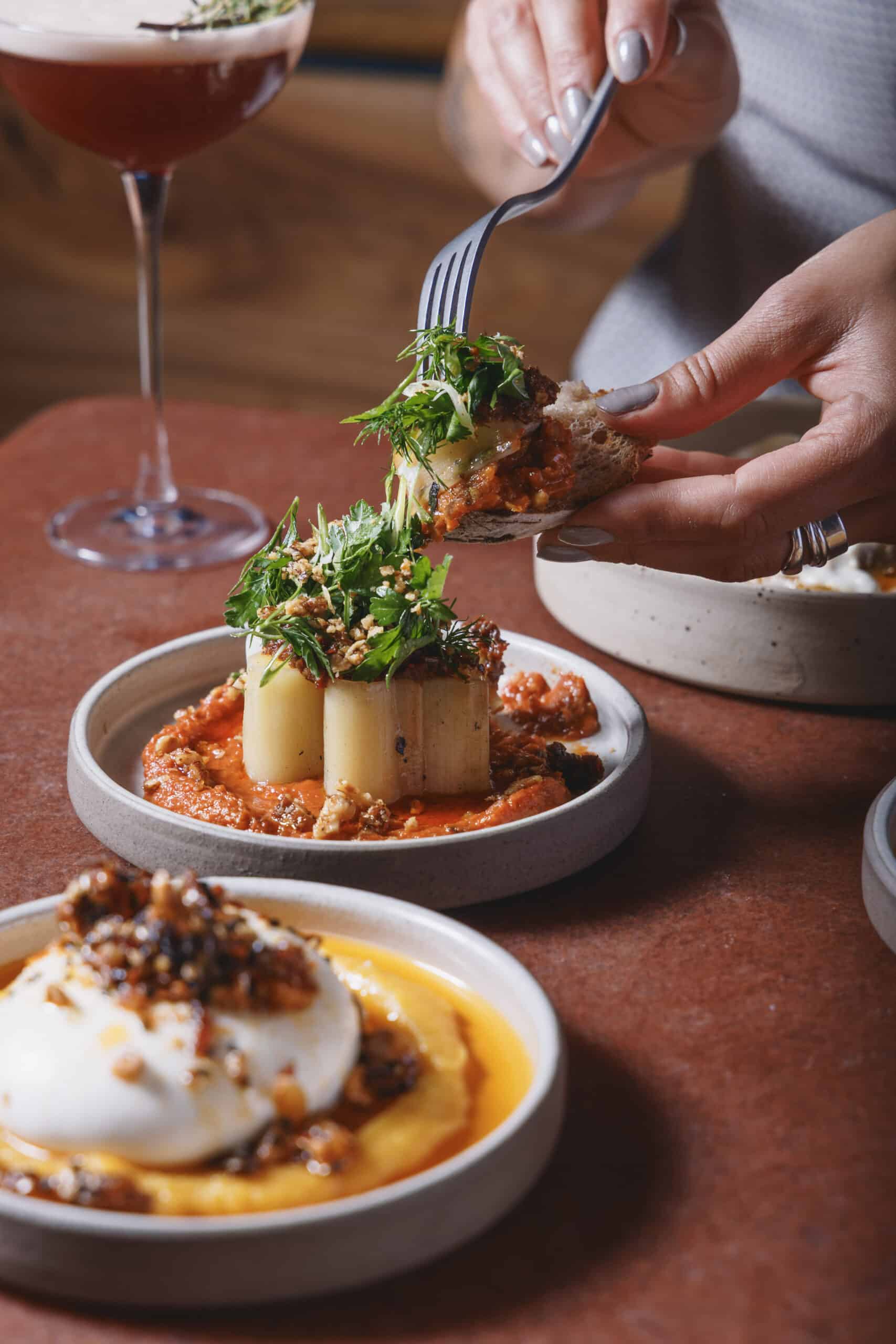 Confit leeks served with muhammara, soft herbs, XO sauce, and confit walnuts at Ara Restaurant in Aldgate East, London.