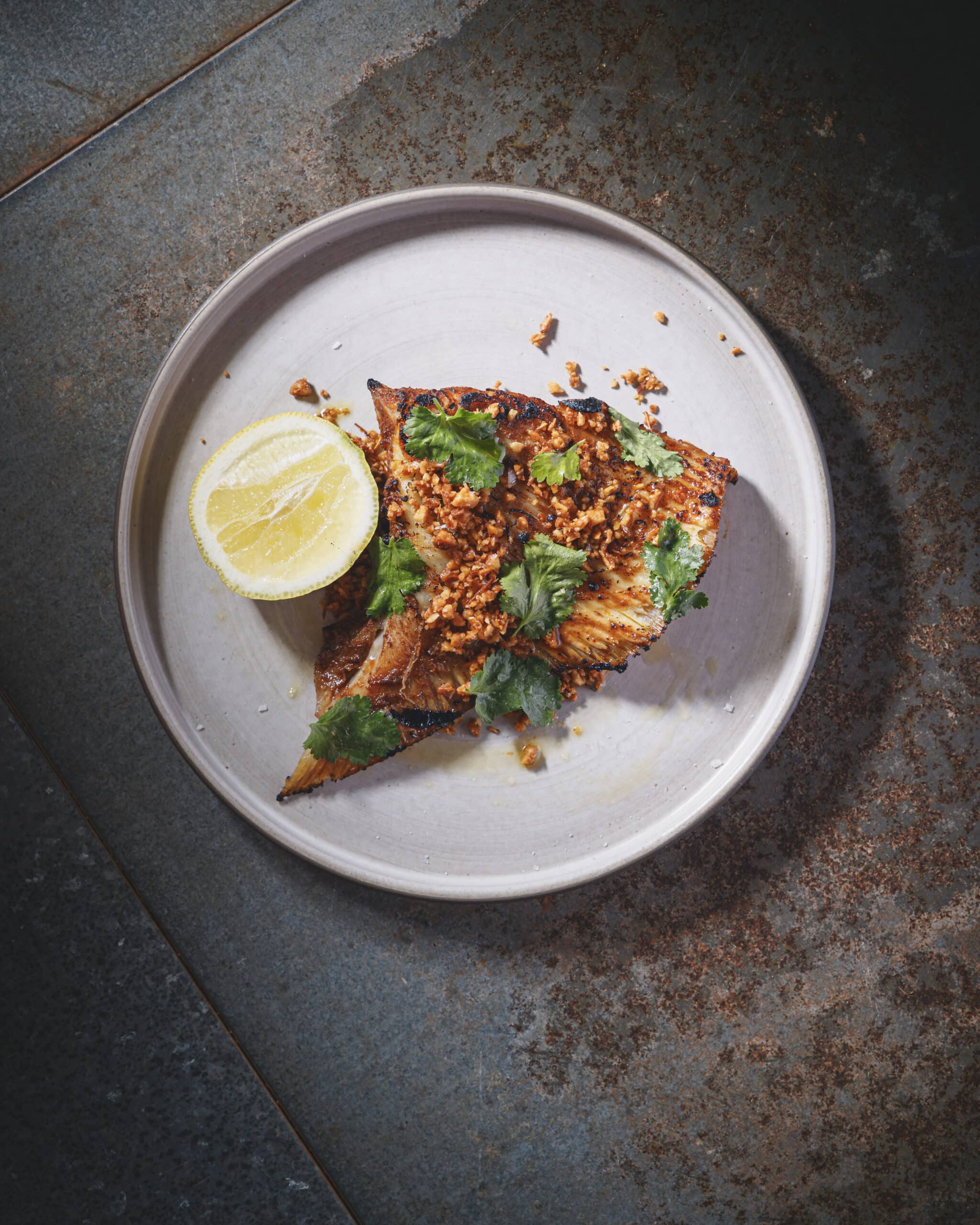 Grilled skate wing glazed with smoky and spicy paste, topped with macadamia and shallot crunch at Ara Restaurant in Whitechapel, London.