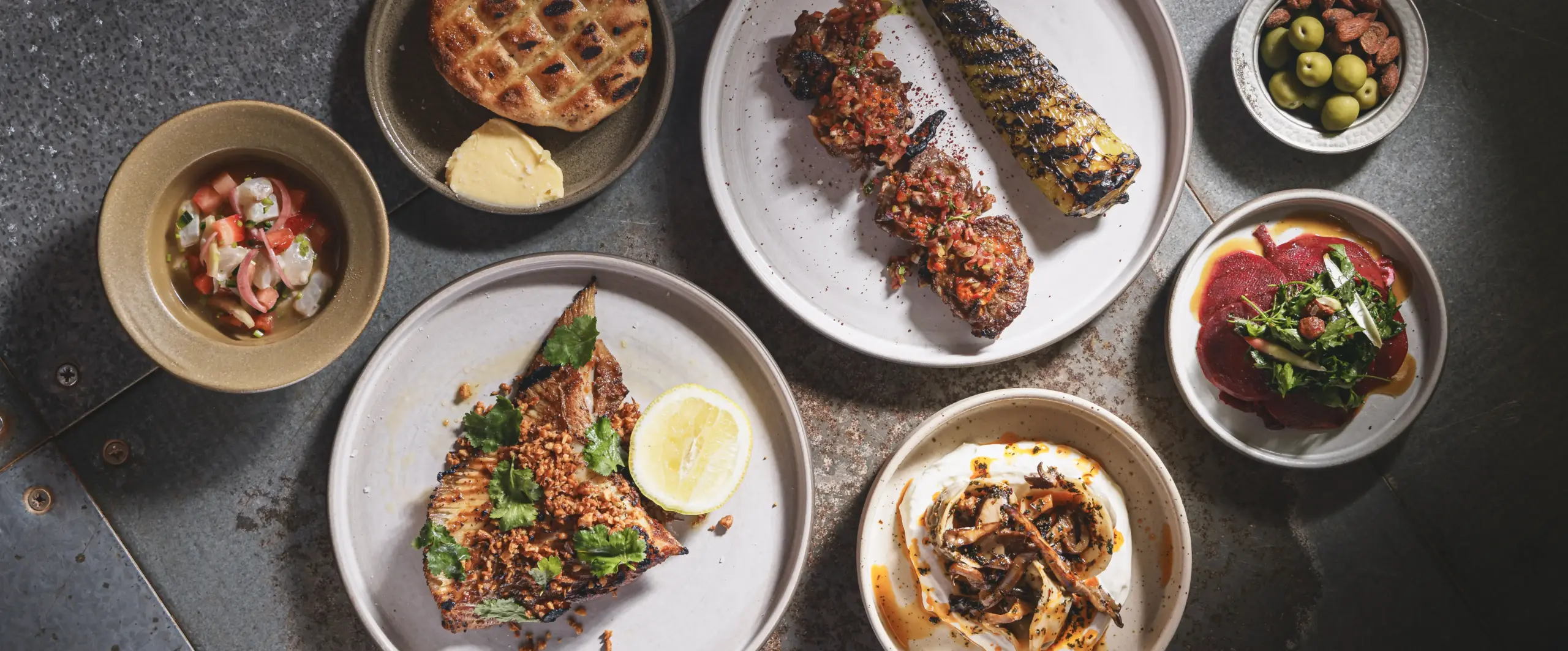 Well travelled small and large plates including grilled skate wing, mushroom dumplings, and lamb skewers at Ara Restaurant in the City of London, near Whitechapel.